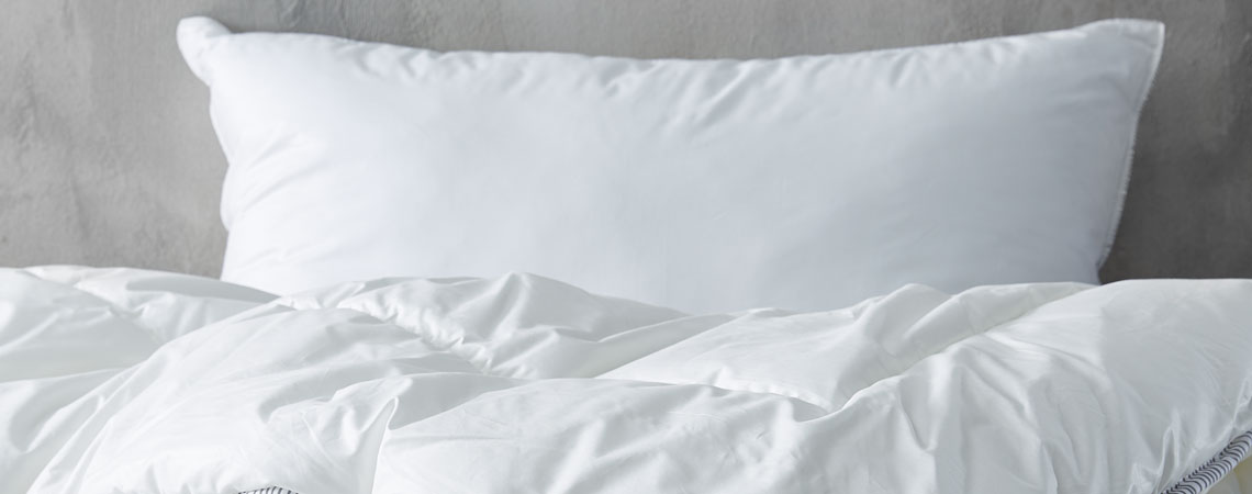 Bettdecke und Kissen mit weißer Bettwäsche