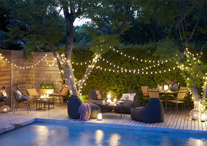 Eine Terrasse dekoriert mit Lichterketten und Gartenlaternen 